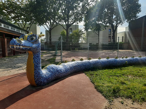 Auf diesem Bild ist ein Kunstwerk in Form eines Drachen zu sehen, der auf dem Schulhof zu finden ist.